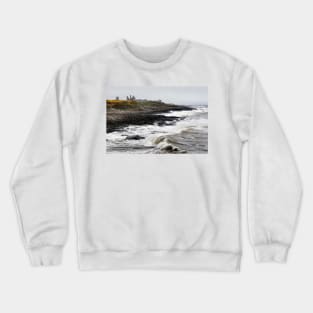 Dunstanburgh castle with rough waves battering the coast in Northumberland, UK Crewneck Sweatshirt